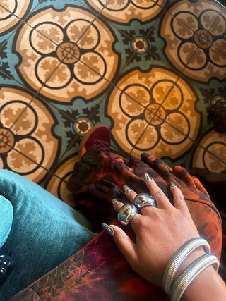 Close up image of Elorae's customer Dara Segbefia posed in silver Metropolis Coil bangles and silver Halo rings against a patterned tile floor.