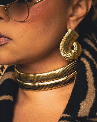 Close-up of Tati Baker wearing gold Metropolis Loop earrings and two gold Metropolis Torque choker necklaces