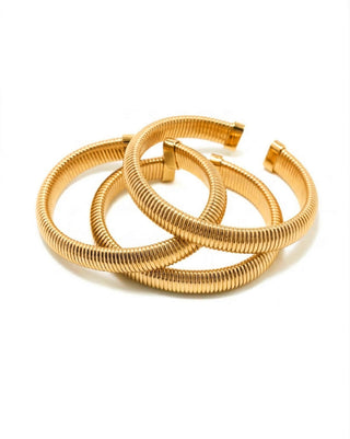 Elorae gold Metropolis Coil Bangles stacked on a white background.